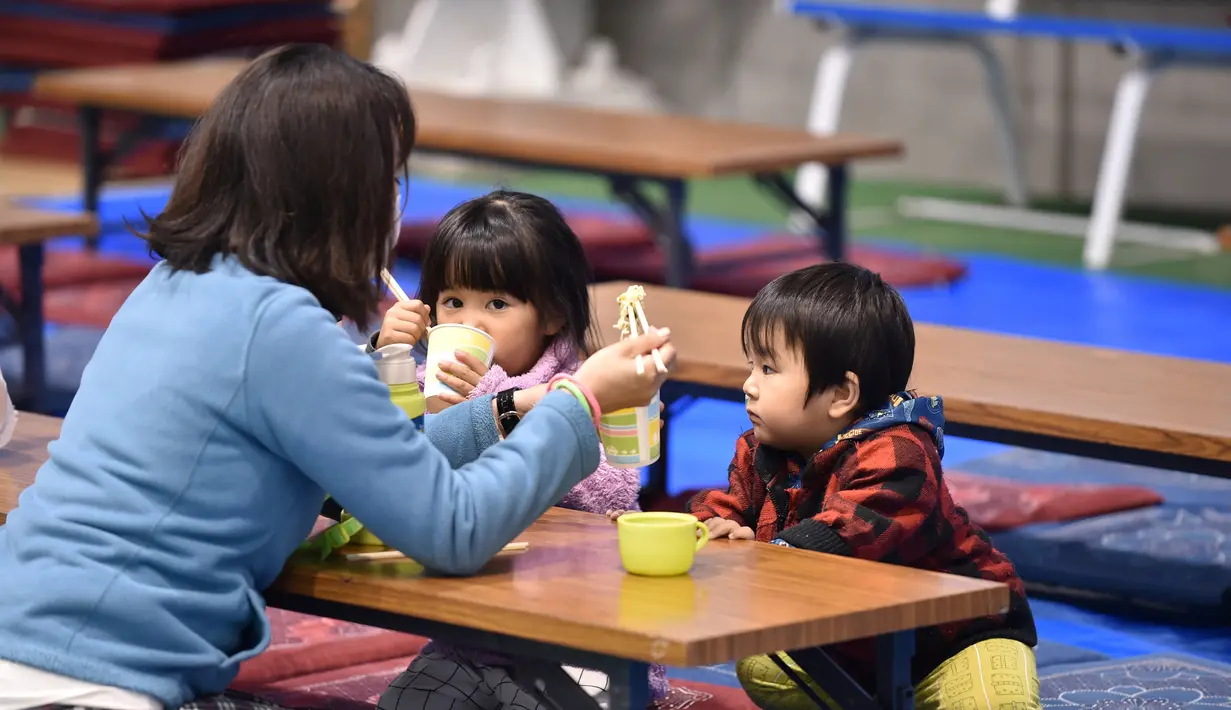 Seorang wanita memberi makan anaknya di tempat penampungan evakuasi di Nagano, Jepang (14/10/2019). Topan Hagibis melanda Jepang pada 12 Oktober, melepaskan angin kencang dan hujan lebat di 36 dari 47 prefektur di negara itu, dan memicu tanah longsor dan banjir besar.  (AFP Photo/Kazuhiro Nogi)