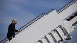 Presiden AS Joe Biden melanjutkan langkahnya setelah tersandung saat menaiki tangga pesawat kepresidenan Air Force One di Pangkalan Udara Andrews, Maryland, Jumat (19/3/2021). Biden yang berusia 78 tahun tidak mengalami cedera dalam kejadian tersebut. (Eric BARADAT/AFP)