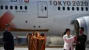 Presiden Olimpiade Tokyo 2020, Yoshiro Mori, menyaksikan dua atlet peraih tiga kali medali emas olimpiade Tadahiro Nomura dan Saori Yoshida menyalakan obor Olimpiade saat tiba dari Yunani di Pangkalan Udara Matsushima, Jepang, Jumat (20/3). (AFP/Philip Fong)