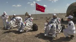 Astronot China Tang Hongbo (kiri), Nie Haisheng (tengah), dan Liu Boming (kanan) sedang diperiksa oleh petugas medis di luar kapsul pendaratan di Gurun Gobi, 17 September 2021. Trio astronot China kembali ke Bumi setelah misi luar angkasa. (CCTV/AFP)