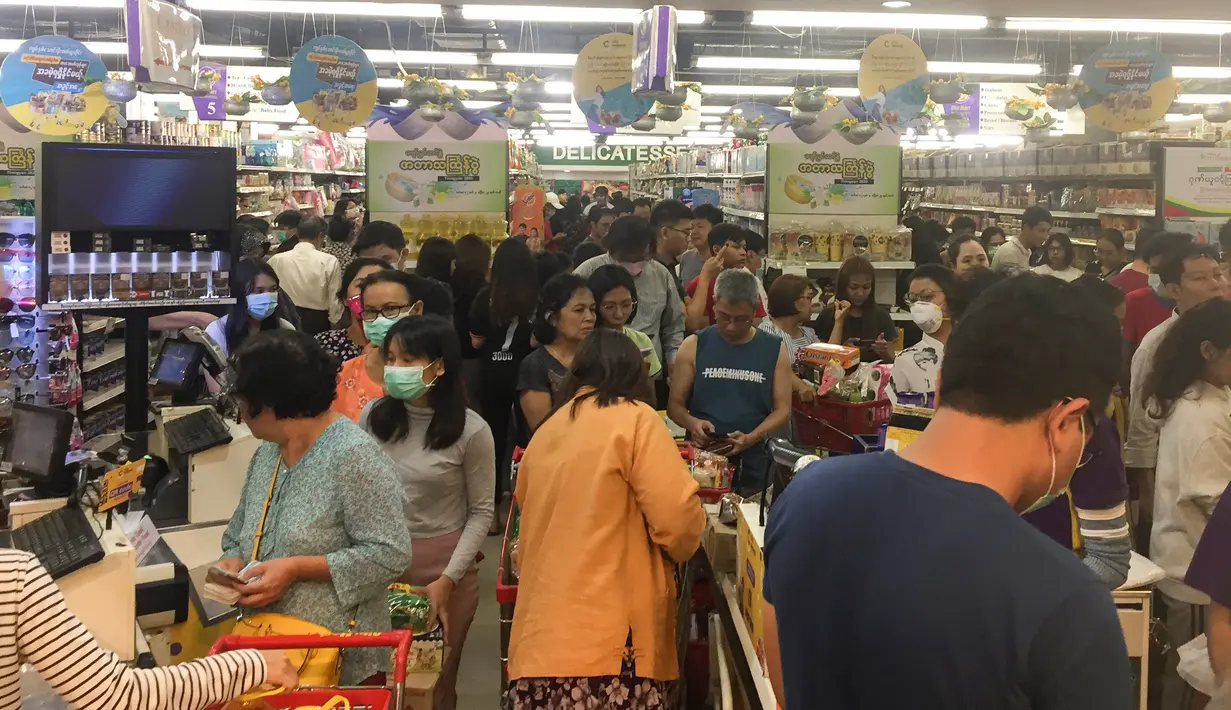 Orang-orang antre untuk membayar makanan dan belanjaan lainnya di supermarket 24 jam di Yangon, Selasa (24/3/2020). Tanggapi kasus pertama Corona COVID-19 pada Senin 23 Maret malam, warga Myanmar memadati pusat perbelanjaan untuk menyetok kebutuhan pokok dan persedian makanan. (AP/Thein Zaw)