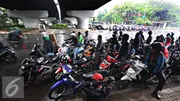 Pengendara sepeda motor berteduh di bawah flyover saat hujan turun, Jakarta, Senin (16/11). Petugas kepolisian akan menerapkan tilang dengan denda maksimal Rp250.000. (Liputan6.com/Immanuel Antonius)