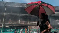 Seorang wanita melintas di depan Pasar Senen yang terbakar, Jakarta, Jumat (20/1). Akibat kebakaran tersebut‎, total kerugian yang alami pedagang diperkirakan mencapai Rp 101,2 miliar. (Liputan6.com/Gempur M Surya)