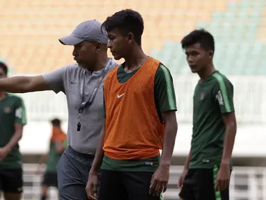 Pelatih Timnas Indonesia U-19, Fakhri Husaini, memberikan arahan kepada Mochammad Supriadi saat latihan di Stadion Pakansari, Bogor, Rabu (2/10). Latihan ini merupakan persiapan jelang AFF U-19 di Vietnam. (Bola.com/Yoppy Renato)