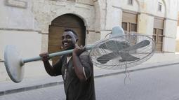 Seorang pekerja Somalia membawa kipas angin tua di Kota Tua Jeddah, Arab Saudi (8/11/2021). Kota Tua Jeddah terletak di pantai timur Laut Merah. Kota ini konon telah berumur 3.000 tahun. (AP Photo/Amr Nabil)