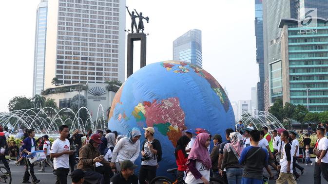Replika bola dunia berukuran besar digelindingkan di sekitar kawasan Bundaran HI, Jakarta, Minggu (16/9). Acara ini bagian dari peringatan Hari Ozon Sedunia 2018 dengan tema Keep Cool and Carry on! The Montreal Protocol. (Liputan6.com/Helmi Fithriansyah)