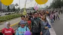 Sejumlah orang yang mengenakan batik berjalan di catwalk sepanjang Jalan Jenderal Sudirman, Jakarta, Minggu (2/10/2022). Kegiatan yang diikuti ratusan orang ini diselenggarakan oleh Bank Mandiri untuk menyambut Hari Batik Nasional yang jatuh setiap tanggal 2 Oktober 2022. (Liputan6.com/Faizal Fanani)