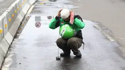 Pengendara Gojek bernama Ari mencari ranjau paku yang berserakan di sekitar Istana Negara, Jakarta, Minggu (14/8). Pria 32 tahun tersebut secara ikhlas mengumpulkan ranjau paku di sekitar Istana Negara.(Liputan6.com/Immanuel Antonius)