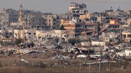 Serangan militer Israel di Gaza memuncak sejak 7 Oktober 2023, hingga kini telah menewaskan lebih dari 45.200 orang yang sebagian besar adalah perempuan dan anak-anak. Tampak dalam foto yang diambil dari perbatasan selatan Israel dengan Jalur Gaza pada 11 Desember 2024, menunjukkan bangunan-bangunan yang hancur di dalam wilayah Palestina. (JACK GUEZ/AFP)