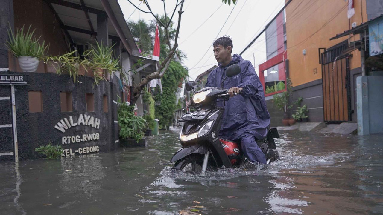 FOTO: Drainase Meluap, Warga Pasar Rebo Terobos Genangan