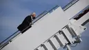Presiden AS Joe Biden saat menaiki Air Force One di Pangkalan Udara Andrews, Maryland, Jumat (19/3/2021). Biden terlihat dengan cepat menahan dirinya agar tidak jatuh dengan berpegangan pada pagar tangga dan berdiri lagi, tetapi kemudian tersandung lagi bahkan sampai berlutut. (Eric BARADAT/AFP)