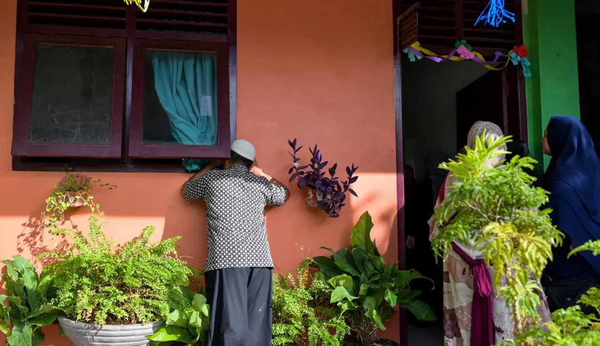 Sejumlah orangtua siswa mengintip anaknya dari jendela dan pintu ruang kelas pada hari pertama sekolah. (Chaideer MAHYUDDIN/AFP)