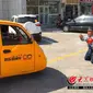 Fu Chongming terlihat tengah berlutut di depan sebuah kendaraan roda tiga untuk menghalagi pengendara dari ilegal parkir di luar toko.