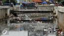 Warga melintasi jembatan kali di Jalan Petojo Utara VI, Jakarta, Senin (26/12). Kali tersebut terlihat kotor akibat ceceran sampah limbah plastik, botol minuman ringan dan sterefoam. (Liputan6.com/Helmi Fithriansyah)