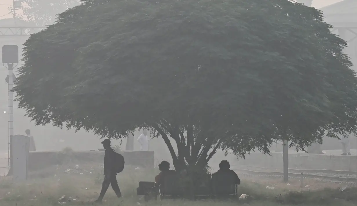 Para penumpang menunggu kereta api di sebuah stasiun kereta api di tengah kondisi kabut asap di Lahore pada tanggal 3 November 2024. (Arif ALI/AFP)