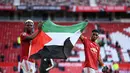Penggawa Manchester United (MU), Paul Pogba dan Amad Diallo mengibarkan bendera Palestina usai ditahan imbang Fulham pada lanjutan Liga Inggris di Stadion Old Trafford, Rabu (19/5/2021) dinihari WIB. Aksi Pogba dan Amad bukan pertama kalinya terjadi. (PHIL NOBLE/POOL/AFP)