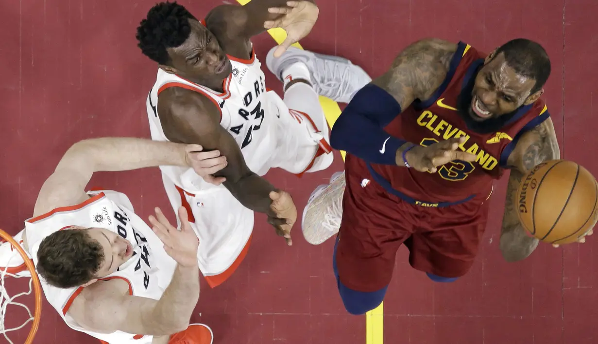 Aksi pemain Cleveland Cavaliers, LeBron James  mencoba melewati adangan dua pemain Toronto Raptors pada lanjutan NBA basketball game di Quicken Loans Arena, (21/3/2018) Cleveland. Cavs menang 132-129. (AP/Tony Dejak)
