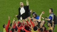 Pemain Maroko merayakan kemenangan timnya atas Spanyol dengan cara melemparkan pelatih kepala Walid Regragui saat babak 16 besar Piala Dunia 2022 yang berlangsung di Education City Stadium, Selasa (06/12/2022). (AP/Abbie Parr)