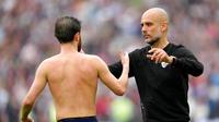 Manajer Manchester City, Pep Guardiola, memberi semangat kepada Bernardo Silva setelah timnya bermain&nbsp;imbang 2-2 kontra West Ham United pada laga pekan ke-37 Premier League di London Stadium, Minggu (15/5/2022) malam WIB.&nbsp;(AP Photo/Kirsty Wigglesworth)
