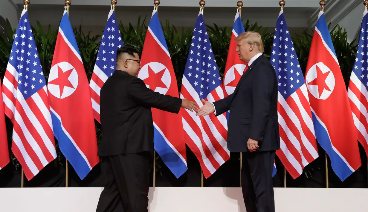 Presiden AS Donald Trump meraih jabat tangan pemimpin Korea Utara Kim Jong-un dalam pertemuan bersejarah di resor Capella, Pulau Sentosa, Singapura, Selasa (12/6). Pertemuan Trump dan Kim diawali dengan jabat tangan bersejarah. (AP/Evan Vucci)