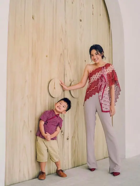 Tampil kompak bersama si kecil, Tiffany Soetanto, istri dari chef Arnold mengenakan off one shoulder blouse warna merah yang dipadukan dengan celana warna cream. Sementara putranya, Arthur mengenakan kemeja merah khas Imlek. (Instagram/tiffanysoetanto).
