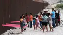 Suasana saat anak-anak bermain jungkat-jungkit yang dipasang di antara pagar pemisah Meksiko dengan Amerika Serikat, Ciudad de Juarez, Meksiko, Minggu (28/7/2019). Jungkat-jungkit tersebut dirancang seorang profesor arsitektur California, Ronald Rael. (AP Photo/Christian Chavez)