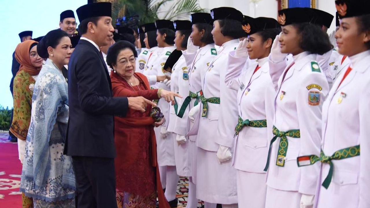 Presiden Jokowi secara simbolik memasangkan pin pengukuhan anggota Paskibraka kepada salah seorang anggota yang ditugaskan sebagai pemimpin upacara.