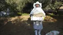 Seorang peternak wanita  membawa sarang madu dari sarang lebah selama panen madu di sepanjang perbatasan Jalur Gaza dengan Israel, di desa Khuza'a, timur Khan Younis, Jalur Gaza selatan, Jumat, 20 Mei 2022. (AP Photo/Adel Hana)