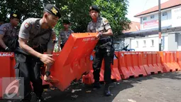 Polisi satuan Brimob mengangkat Water Barrier untuk barikade pengamanan menuju Dermaga Nusakambangan, Cilacap, Jawa Tengah, Rabu (27/7). Menjelang eksekusi Tahap 3 sejumlah persiapan dilakukan oleh Lapas Nusakambangan. (Liputan6.com/Helmi Afandi)
