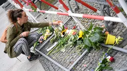 Seorang wanita meletakkan bunga di depan Kedutaan Besar Perancis di Berlin, Jerman (15/7). Karangan bunga tersebut untuk menghormati para korban teror Truk Maut saat perayaan hari Bastille di Nice. (AFP PHOTO/John MacDougall)