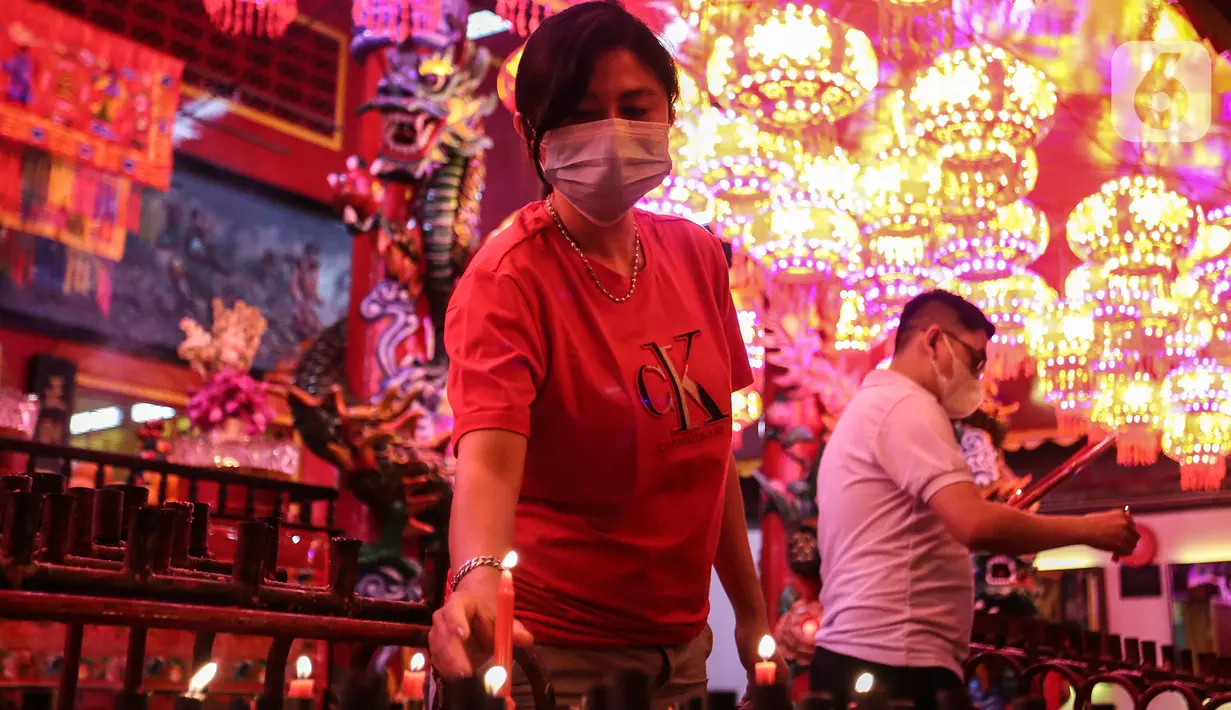 Seorang warga Tionghoa mengambil lilin saat beribadah malam perayaan Tahun Baru Imlek 2573 di Vihara Amurva Bhumi, Jakarta, Senin (31/1/2022). Ibadah Imlek pada tahun ini dilakukan pembatasan sampai pukul 20.00 akibat pemberlakuan PPKM level tiga di Jakarta. (Liputan6.com/Johan Tallo)