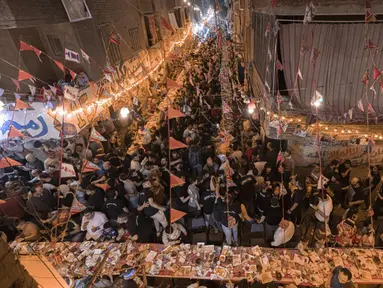 Umat muslim berkumpul di meja sepanjang jalan untuk berbuka puasa bersama dalam jamuan buka puasa massal pada hari ke-15 bulan suci Ramadhan di pinggiran Matariya, timur laut Kairo, Mesir, 16 April 2022. (Khaled DESOUKI/AFP)