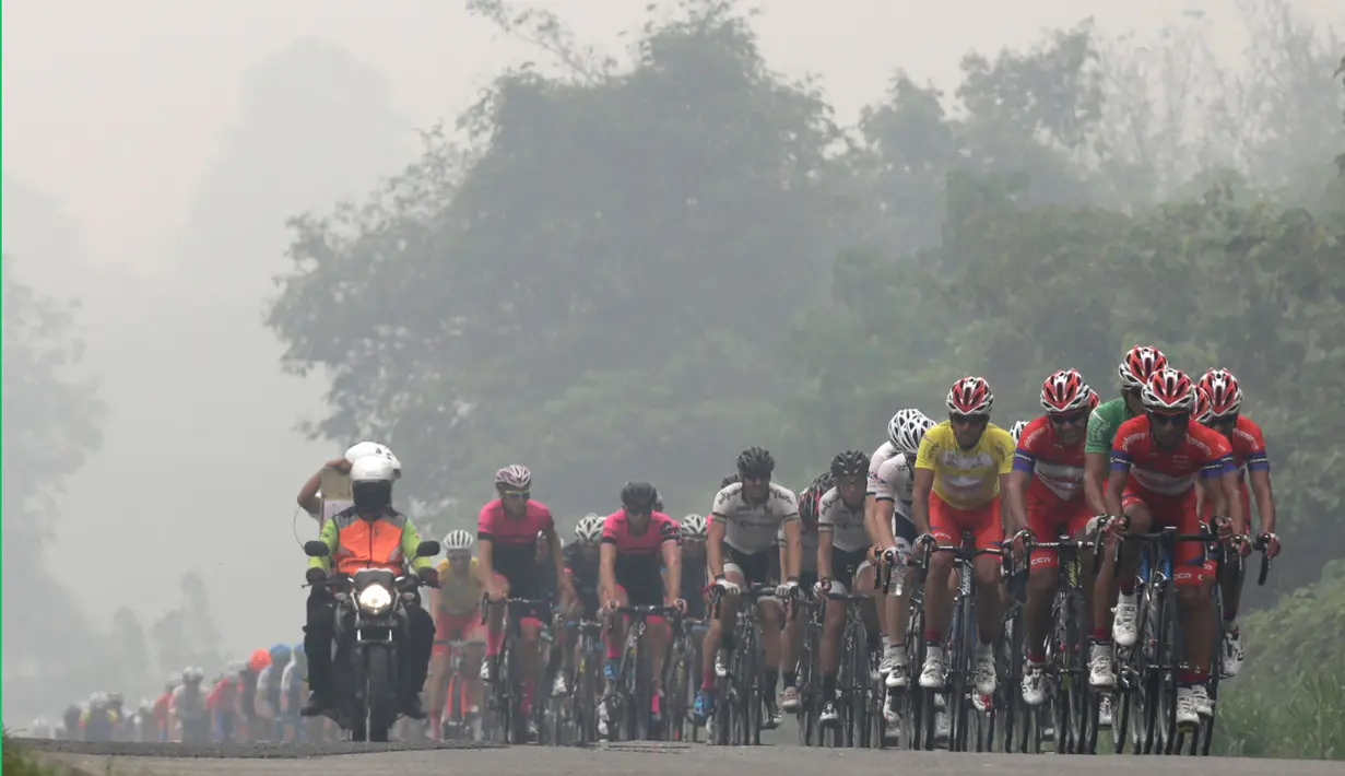 Di tengah pekatnya kabut asap, para pebalap terus melaju ke finis Etape 3 Tour de Singkarak 2015 di Dharmasraya, Sumatra Barat, Senin (5/10/2015). (Bola.com/Arief Bagus)