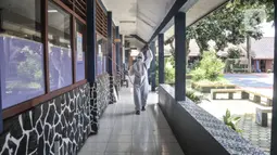 Petugas sekolah menyemprotkan disinfektan di koridor usai Pembelajaran Tatap Muka (PTM) 100 persen di SMP Negeri 9 Depok, Cipayung, Senin (24/1/2022). Pihak sekolah melakukan penyemprotan disinfektan secara rutin seiring dimulainya pelaksanaan PTM 100 persen di Depok. (merdeka.com/Iqbal S Nugroho)