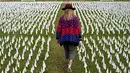 Seniman Suzanne Brennan Firstenberg berjalan di antara ribuan bendera putih yang ditanam untuk mengenang warga Amerika yang meninggal karena COVID-19 di dekat Stadion RFK di Washington, Selasa (27/10/2020). Instalasi seni publik ini disebut "In America, How Could This Happen.” (AP/Patrick Semansky)