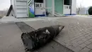 Bagian dari rudal terlempar hingga ke depan sebuah toko setelah ledakan gudang senjata di pangkalan militer Ukraina di Balakliya, Kamis (23/3). Sekitar 20.000 warga terpaksa dievakuasi akibat kejadian tersebut. (AP Photo/Mykhailo Andriiv)