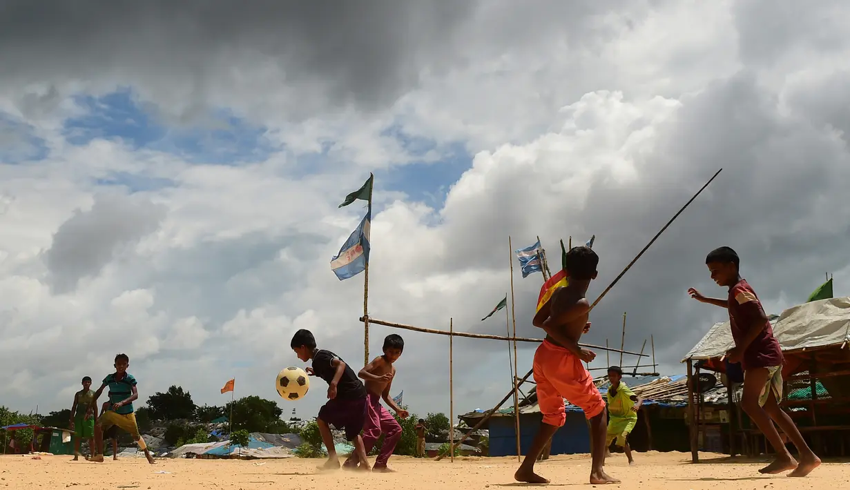 Anak-anak Rohingya bermain sepak bola di kamp pengungsi Kutupalong di Ukhia, Bangladesh, 19 Juli 2018. Bendera Argentina dan Brasil bahkan masih berkibar berdampingan dengan bendera Bangladesh di kamp pengungsi terbesar di dunia. (AFP/Munir UZ ZAMAN)