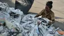 Seorang ibu dengan cekatan merapikan lembaran-lembaran koran sisa alat salat Id di wilayah Jatinegara, Jakarta, Rabu (6/7/2016). Sisa koran alas salat menjadi berkah tersendiri bagi pengumpul koran bekas. (Liputan6.com/Yoppy Renato)