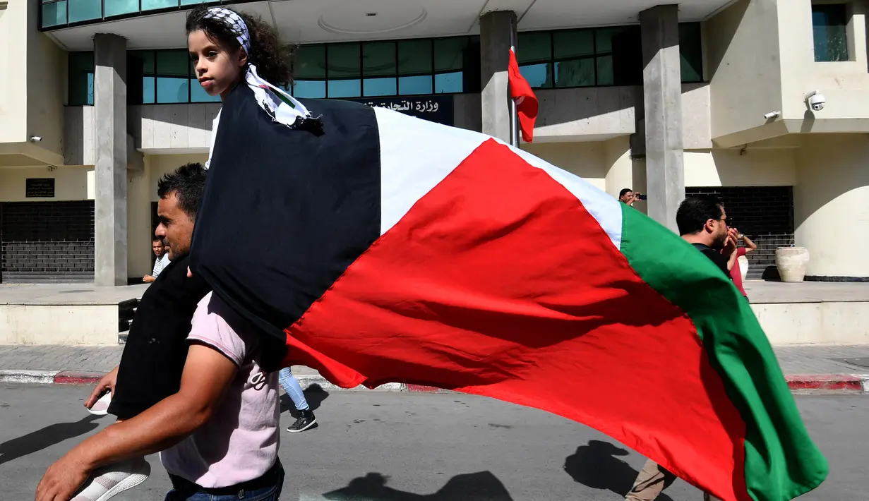 Orang-orang melambaikan bendera Palestina selama protes untuk mengekspresikan solidaritas mereka terhadap Gaza di ibu kota Tunisia, Tunis, pada 21 Oktober 2023, di tengah pertempuran yang sedang berlangsung antara Israel dan kelompok Palestina Hamas. (FETHI BELAID / AFP)