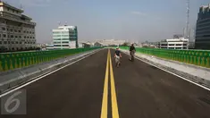 Seorang anak ditemani orang tuanya bersepeda di sepanjang jalan layang (elevated) Transjakarta rute Cileduk-Tendean di Jakarta, Minggu (26/2). Belum beroperasinya jalan layang tersebut dimanfaatkan warga untuk berolahraga. (Liputan6.com/Immanuel Antonius)