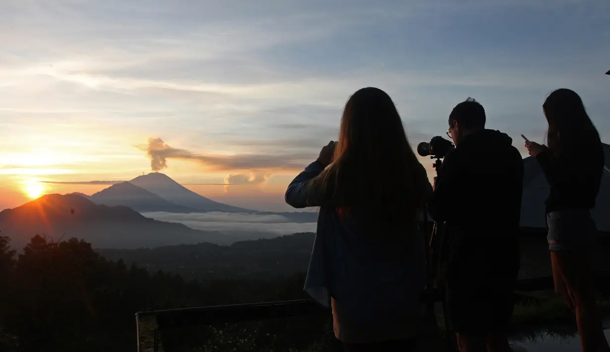 Wisatawan mengambil gambar sambil menikmati matahari terbit (sunrise) di Gunung Agung dari Kintamani, Bali, Rabu (13/12). BNPB menegaskan bahwa kondisi Pulau Bali aman bagi wisatawan meski Gunung Agung berstatus siaga. (AP Photo/Firdia Lisnawati)