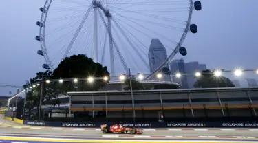 Pembalap Ferrari Formula 1, Sebastian Vettel saat melakukan sesi latihan jelang Grand Prix Singapura F1 di Sirkuit Marina Bay (18/9/2015). Kabut asap yang menyelimuti sirkuit tak menyurutkan pembalap untuk tetap melakukan pemanasan. (REUTERS/Tim Chong)