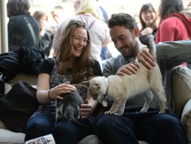 Sepasang suami istri mengajak kucing kesayangan mereka untuk bermain di Cat Cafe, New York, Amerika Serikat (AFP PHOTO/Emmanuel Dunand)