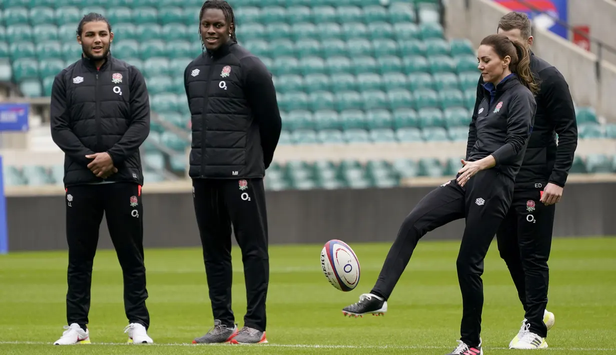 Kate Middleton, Duchess of Cambridge, melakukan tendangan di sebelah pemain tim rugby union putra Inggris, Lewis Ludlam, Maro Itoje, dan Elliot Daly selama sesi pelatihan di Stadion Twickenham, di London (2/2/2022). (AP Photo/Alberto Pezzali)