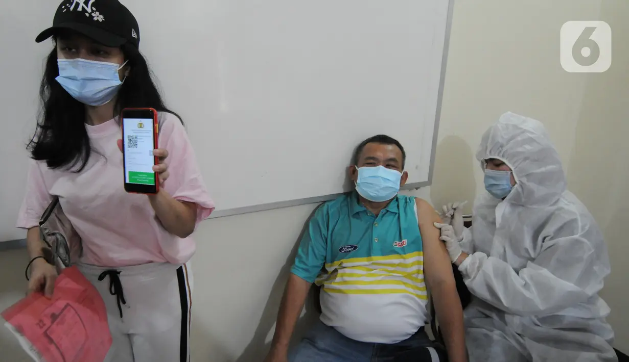 Petugas menyuntikkan vaksin covid-19 kepada warga di Polsek Pamulang, Tangerang Selatan, Kamis (1/7/2021). Sebanyak 10 ribu dosis vaksin untuk warga 18 tahun ke atas dibagikan di wilayah Polres Tangerang Selatan dalam rangka HUT Bhayangkara Ke-75 yang jatuh pada hari ini. (merdeka.com/Arie Basuki)