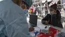 Seorang wanita menunggu untuk swab COVID-19 di sebuah pusat kesehatan darurat di sebuah jalan di pusat kota Lima, Rabu (5/1/2022). Peru melaporkan negara itu secara resmi menghadapi gelombang ketiga COVID-19 karena peningkatan kasus infeksi setelah perayaan Natal dan Tahun Baru. (Cris BOURONCLE/AFP)