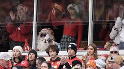 Taylor Swift memberikan dukungan untuk sang kekasih, Travis Kelce saat pertandingan NFL (National Football League) antara Kansas City Chiefs melawan Las Vegas Raiders di Arrowhead Stadium, Kansas, Amerika Serikat, Selasa (26/12/2023) WIB. Ia terlihat mengenakan busana bernuansa natal dengan memadukan sweater merah, plaid miniskirt, dan topi Santa Klaus bertuliskan 87. (AP Photo/Charlie Riedel)