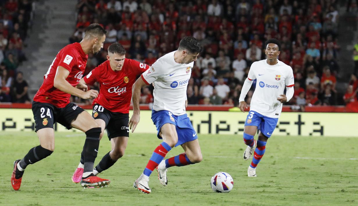 Pemain Barcelona, Robert Lewandowski, berusaha melewati pemain Real Mallorca pada laga pekan ke-7 La Liga 2023/2024, di Stadion Mallorca Son Moix Rabu (27/9/2023). Kedua tim bermain sama kuat 2-2. (AP Photo/Francisco Ubilla)