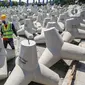 Pekerja menyelesaikan proses pembuatan tetrapod untuk pengaman Pantai Singapura di Plant Karawang PT Waskita Beton Precast, Jawa Barat, Rabu (17/6/2020). Era new normal, produksi beton cetak dan pra cetak terus berjalan dengan menerapkan protokol kesehatan. (Liputan6.com/Fery Pradolo)