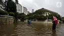 Warga berpose di tengah banjir di Jalan Hang Lekir, Kebayoran Lama, Jakarta Selatan, Rabu (1/1/2020). Banjir tersebut disebabkan karena tingginya intensitas hujan yang mengguyur sejak Selasa (31/12/2019). (Liputan6.com/Johan Tallo)